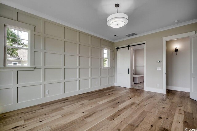 1142 Fiddlehead Way, Myrtle Beach, SC 29579 - unfurnished bedroom with a decorative wall, ornamental molding, a barn door, light wood finished floors, and multiple windows