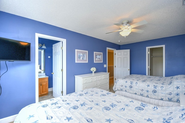 6172 Catalina Dr Unit 515, North Myrtle Beach, SC 29582 - bedroom with ceiling fan, connected bathroom, a walk in closet, and a textured ceiling