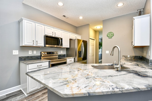 6172 Catalina Dr Unit 515, North Myrtle Beach, SC 29582 - kitchen with stainless steel appliances, wood finished floors, white cabinets, a textured ceiling, and a peninsula