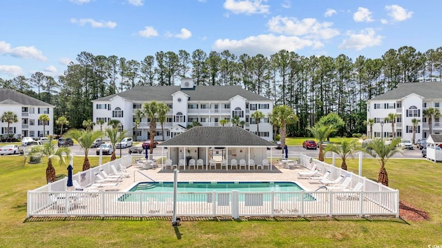 rear view of property with a community pool, a patio, and view of scattered trees