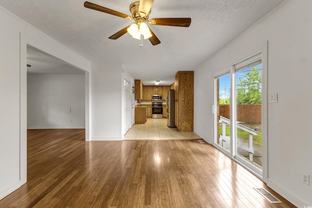 unfurnished living room featuring light wood finished floors, a ceiling fan, baseboards, and a textured ceiling