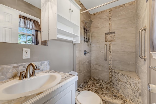 full bath featuring toilet, a tile shower, and vanity