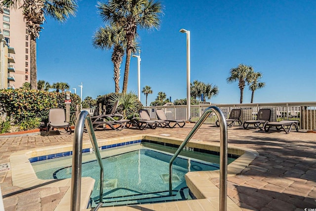 view of swimming pool featuring a community hot tub, a patio area, and fence