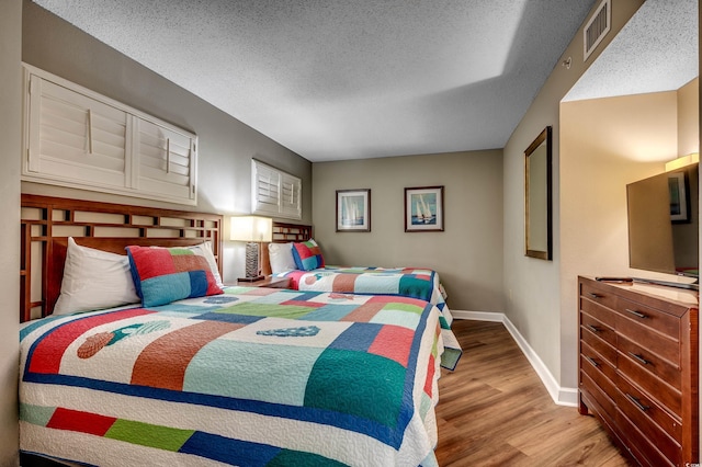 bedroom featuring wood finished floors, baseboards, and a textured ceiling