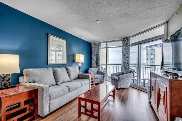 living area with expansive windows, wood finished floors, and a textured ceiling