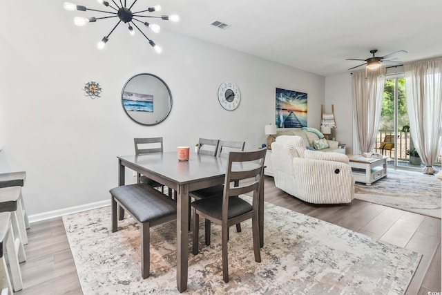 dining area featuring wood finished floors, a chandelier, a ceiling fan, and baseboards
