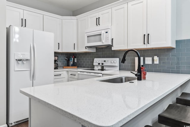 kitchen featuring white appliances, a peninsula, white cabinetry, and light stone countertops