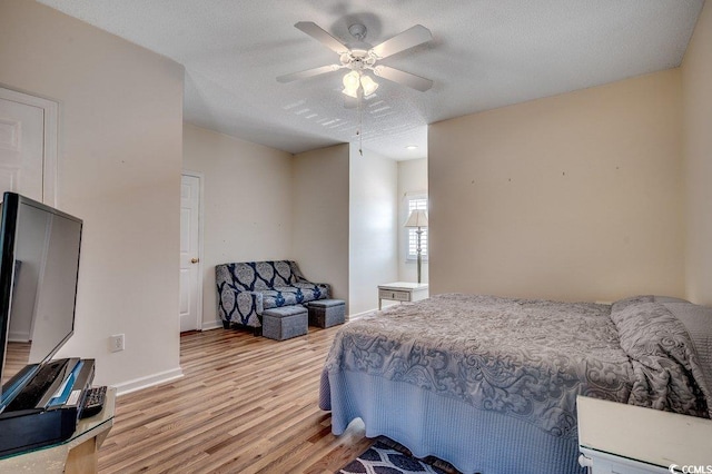 bedroom featuring light wood-style floors, baseboards, ceiling fan, and a textured ceiling