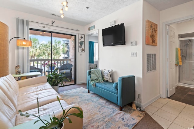 living area featuring baseboards, tile patterned floors, and a textured ceiling