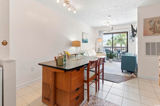 kitchen with light tile patterned floors, a textured ceiling, open floor plan, dark countertops, and baseboards
