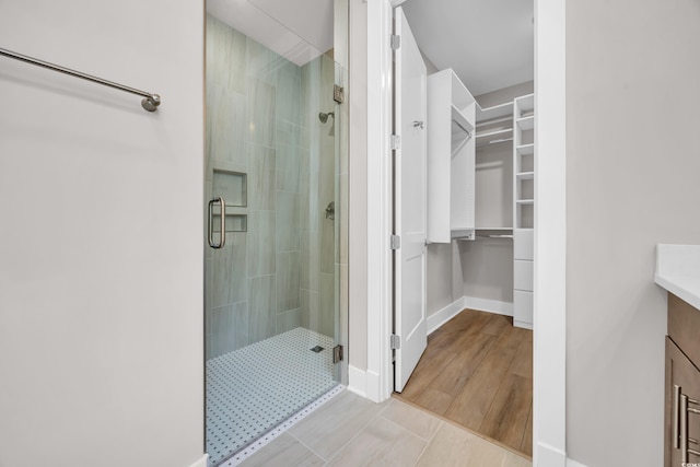 bathroom featuring a shower stall, a walk in closet, vanity, and baseboards