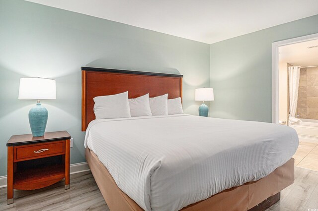 201 S Ocean Blvd Unit 1112, Myrtle Beach, SC 29577 - bedroom featuring light wood-type flooring, baseboards, and connected bathroom