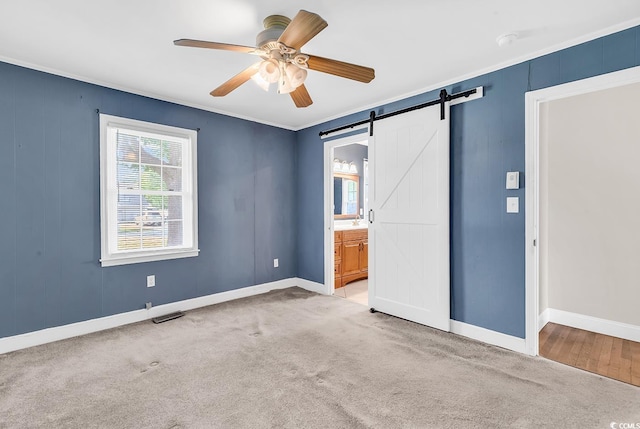 3001 Wiley Dr, North Myrtle Beach, SC 29582 - unfurnished bedroom featuring a barn door, baseboards, carpet flooring, ornamental molding, and connected bathroom