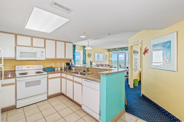 kitchen with white appliances, a peninsula, white cabinetry, a sink, and a textured ceiling