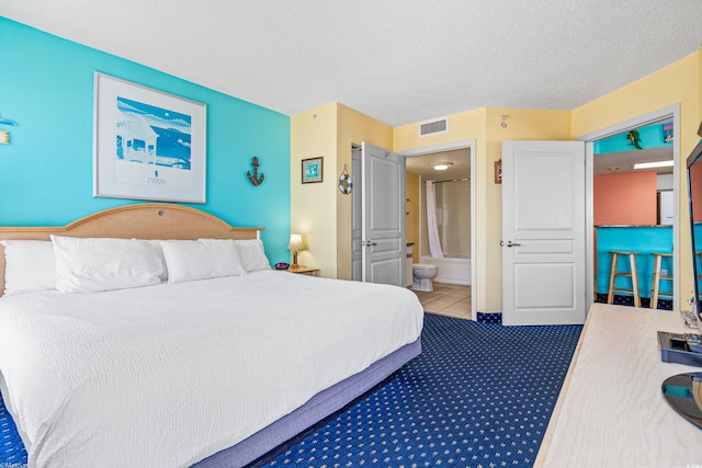 carpeted bedroom with a textured ceiling and ensuite bath
