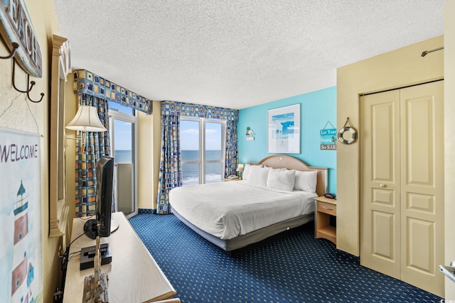 bedroom with access to outside, carpet floors, and a textured ceiling