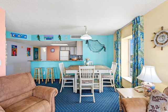 carpeted dining area featuring a textured ceiling and bar area