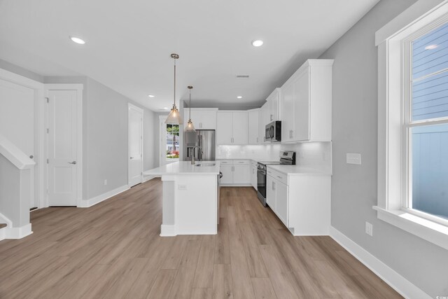 1961 Indigo Cove Ln, Calabash, NC 28467 - kitchen featuring stainless steel appliances, light countertops, white cabinetry, decorative light fixtures, and light wood-type flooring