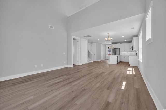 1961 Indigo Cove Ln, Calabash, NC 28467 - unfurnished living room featuring a chandelier, light wood-type flooring, stairway, baseboards, and recessed lighting