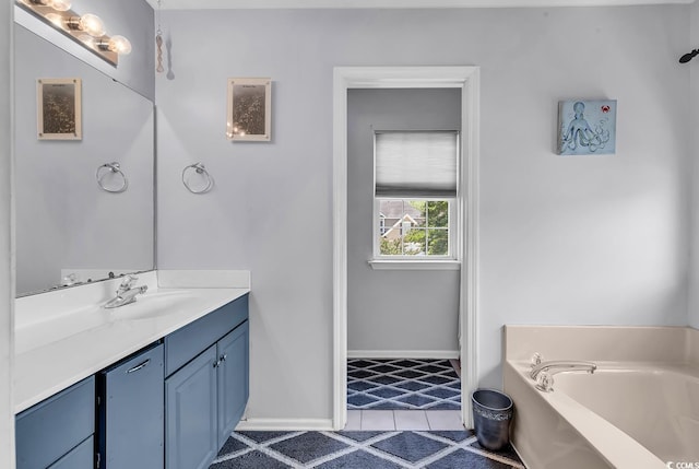 full bath featuring a garden tub, vanity, tile patterned floors, and baseboards