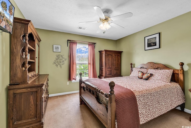 bedroom featuring light carpet, baseboards, ceiling fan, and a textured ceiling