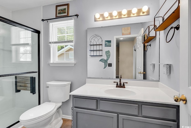 bathroom featuring toilet, vanity, a stall shower, and baseboards