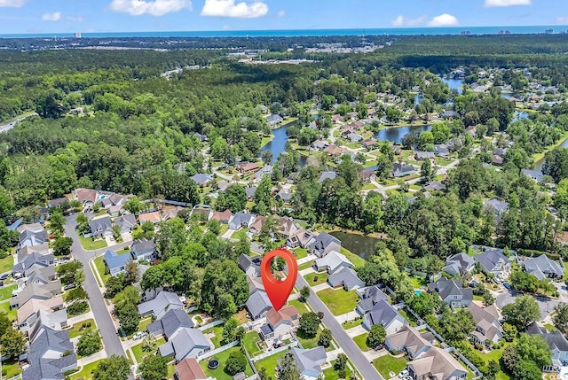 aerial view of property and surrounding area featuring a large body of water, nearby suburban area, and a forest
