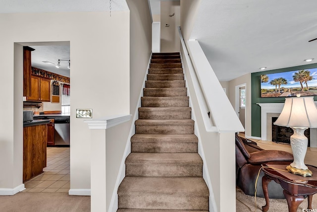 staircase with a fireplace, carpet, tile patterned flooring, and healthy amount of natural light