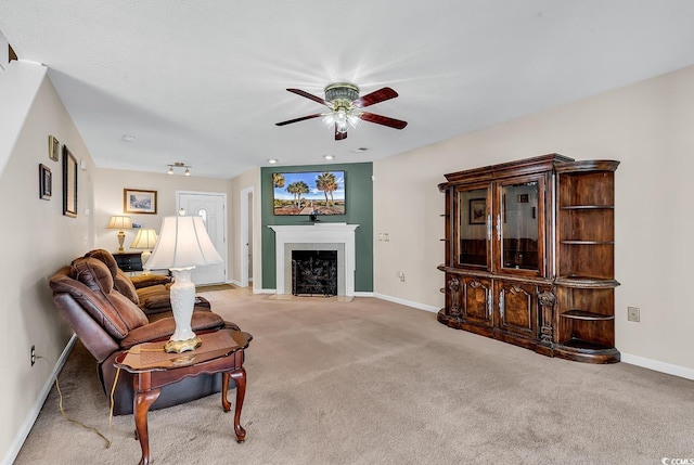carpeted living room with a ceiling fan, baseboards, and a fireplace with flush hearth
