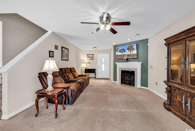 living room with a ceiling fan, light carpet, baseboards, and a fireplace with raised hearth