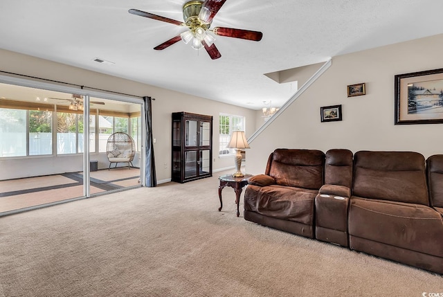 carpeted living area with a ceiling fan, a chandelier, and baseboards