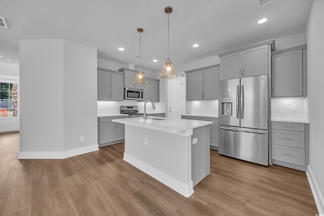 kitchen featuring appliances with stainless steel finishes, gray cabinets, tasteful backsplash, light countertops, and recessed lighting