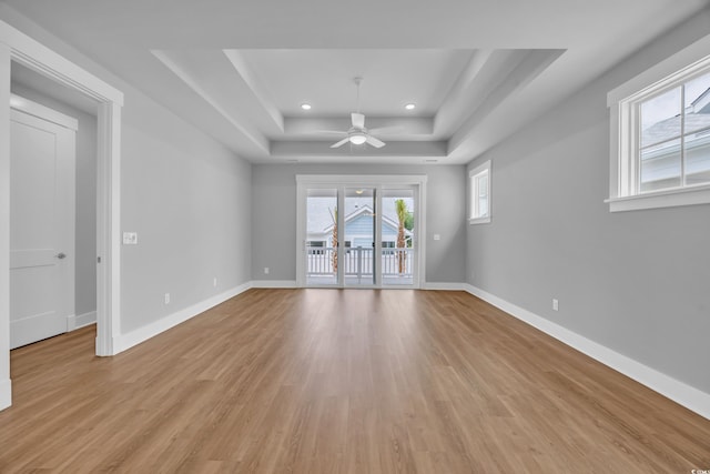 empty room with a raised ceiling, a ceiling fan, light wood-style floors, baseboards, and recessed lighting