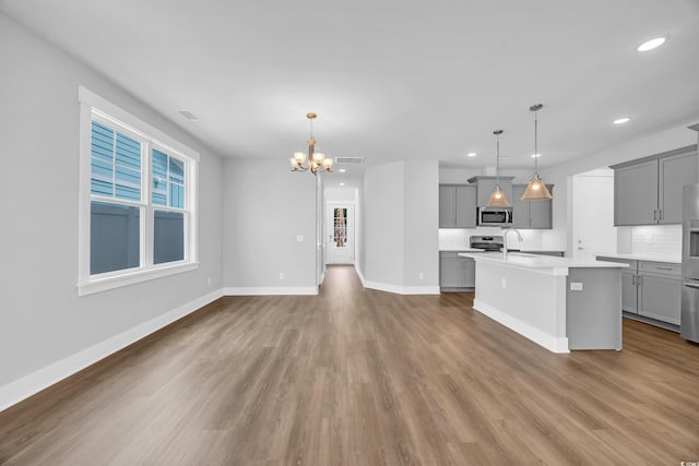 kitchen featuring gray cabinetry, stainless steel appliances, light countertops, a chandelier, and recessed lighting