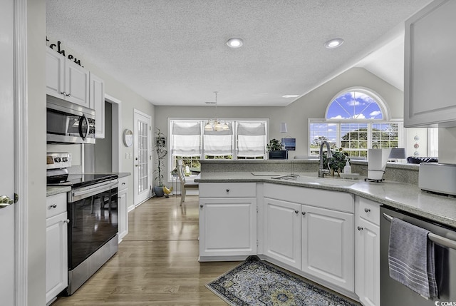 kitchen with appliances with stainless steel finishes, a sink, white cabinets, light wood-style flooring, and a textured ceiling