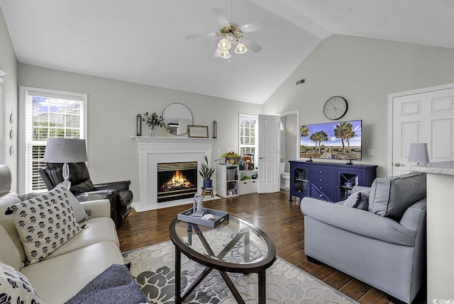 living area featuring ceiling fan, wood finished floors, a tile fireplace, and high vaulted ceiling
