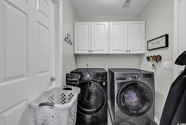 clothes washing area with independent washer and dryer, cabinet space, and a textured ceiling