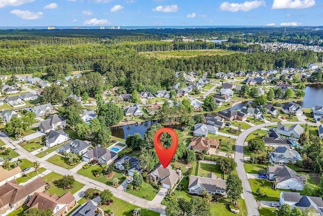 view of property location with a heavily wooded area, nearby suburban area, and a large body of water