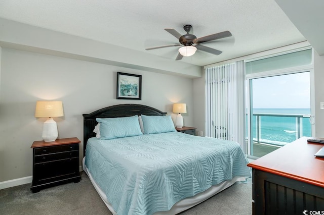 bedroom featuring carpet, access to outside, a water view, a ceiling fan, and a textured ceiling