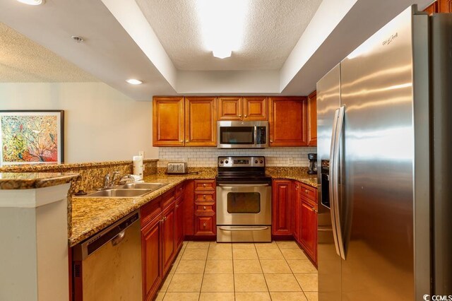 kitchen with stainless steel appliances, a sink, a peninsula, backsplash, and light tile patterned floors