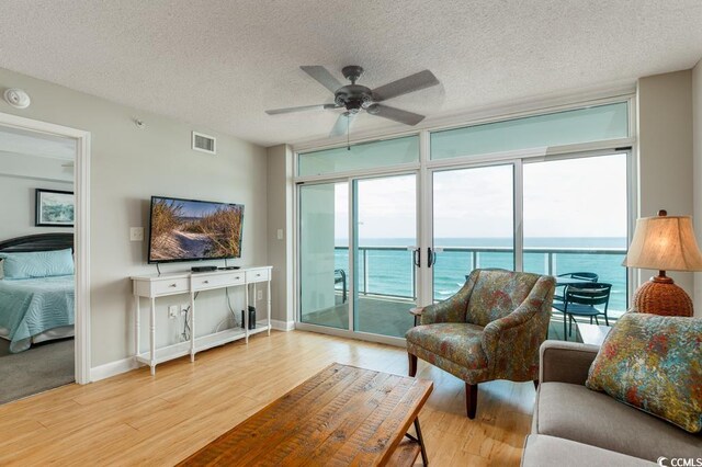 1903 S Ocean Blvd S Unit 808, North Myrtle Beach, SC 29582 - living area featuring light wood-style floors, ceiling fan, a textured ceiling, expansive windows, and baseboards
