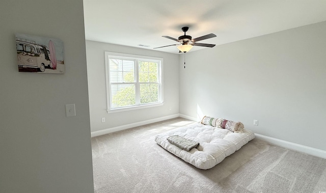 living area with baseboards, ceiling fan, and carpet flooring