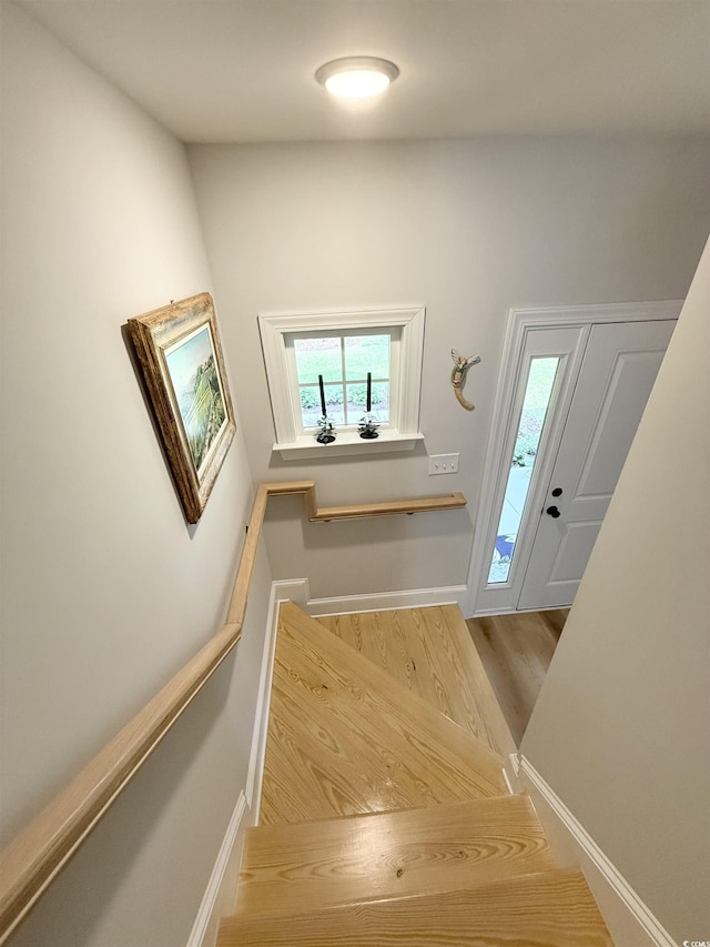 staircase featuring wood finished floors and baseboards