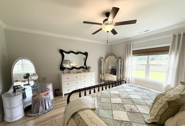 bedroom with light wood-style flooring, crown molding, and a ceiling fan