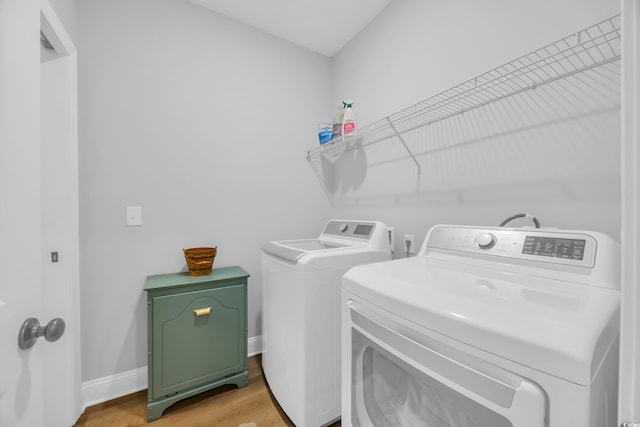 laundry area featuring washing machine and dryer, light wood-style flooring, and baseboards