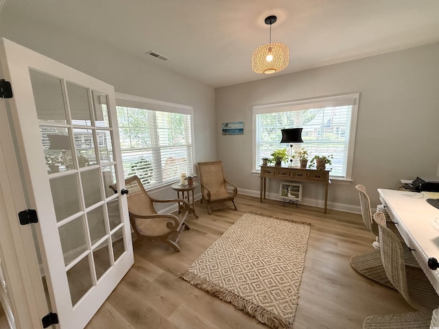 living area with light wood-style flooring, baseboards, and a desk
