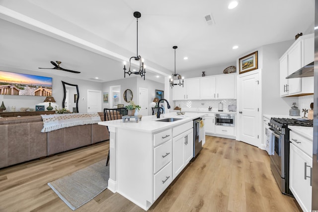 kitchen with stainless steel appliances, a sink, open floor plan, recessed lighting, and range hood