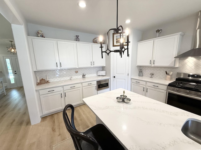 kitchen featuring built in microwave, gas stove, white cabinets, backsplash, and light wood finished floors