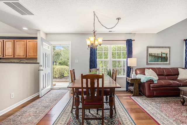 dining space featuring a chandelier, dark wood-style flooring, plenty of natural light, a textured ceiling, and baseboards