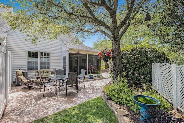 view of patio featuring a sunroom and fence